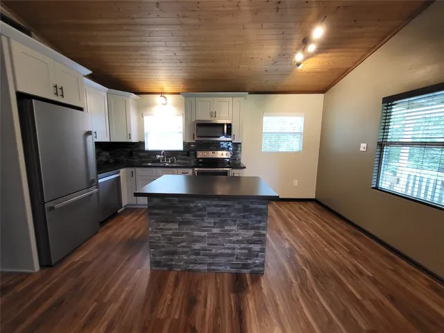 a kitchen with kitchen island a counter space a sink appliances and cabinets