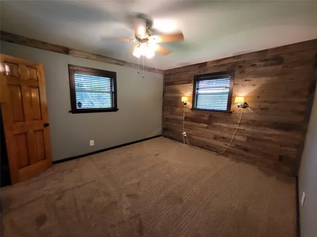 a view of an empty room with window and chandelier fan