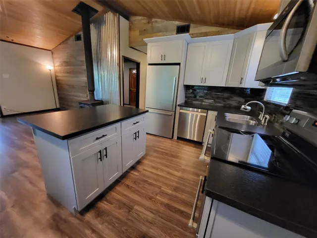 a kitchen with kitchen island granite countertop a sink stove and refrigerator