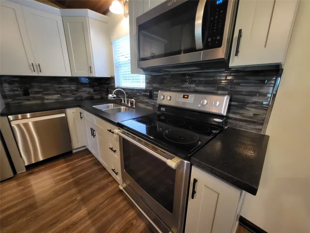 a kitchen with stainless steel appliances granite countertop a stove a sink and a microwave