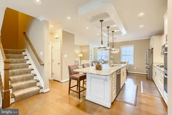 a view of a kitchen with kitchen island stainless steel appliances wooden floor and dining table