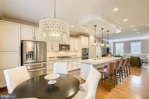 a kitchen with stainless steel appliances granite countertop a stove refrigerator a dining table and chairs with wooden floor