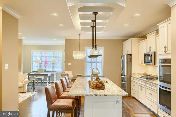 a kitchen with stainless steel appliances kitchen island granite countertop a kitchen island and chairs in it