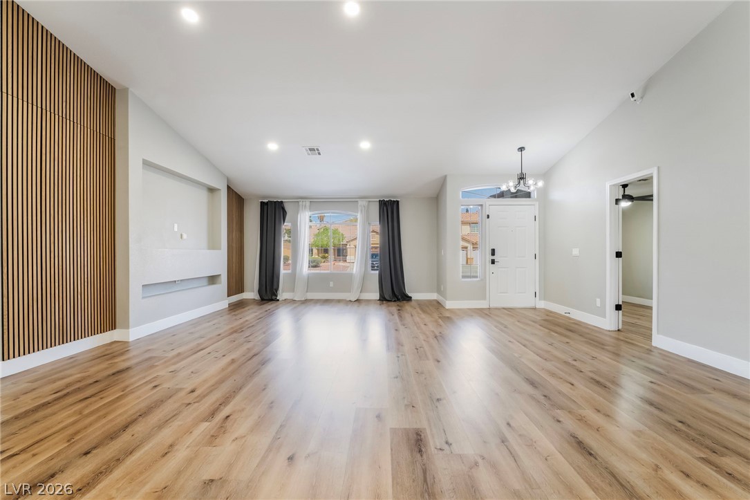 9171 West Viking Road Las Vegas, NV 89147 - Photo 10 of 43 Natural wood flooring complements this generously proportioned living area, offering a warm and inviting atmosphere.