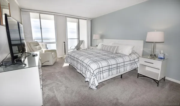 a bedroom with a bed a large window and walk in closet with a mirror