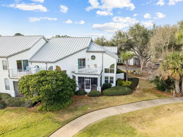 a view of a white house next to a yard with big trees