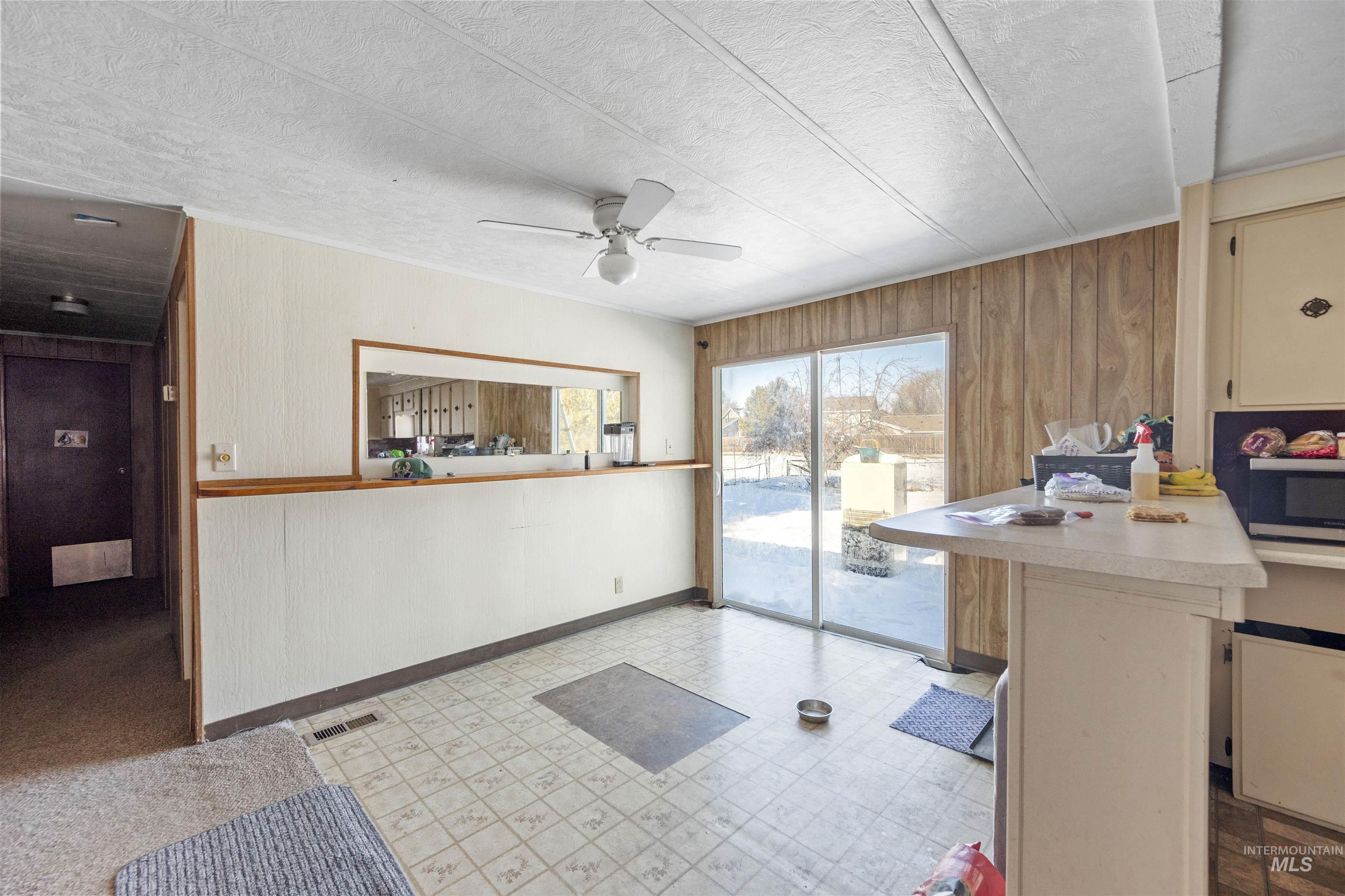 2382 East Syringa Street Eagle, ID 83616 - Photo 19 of 25 Kitchen with light flooring, wood walls, light countertops, a ceiling fan, and stainless steel microwave
