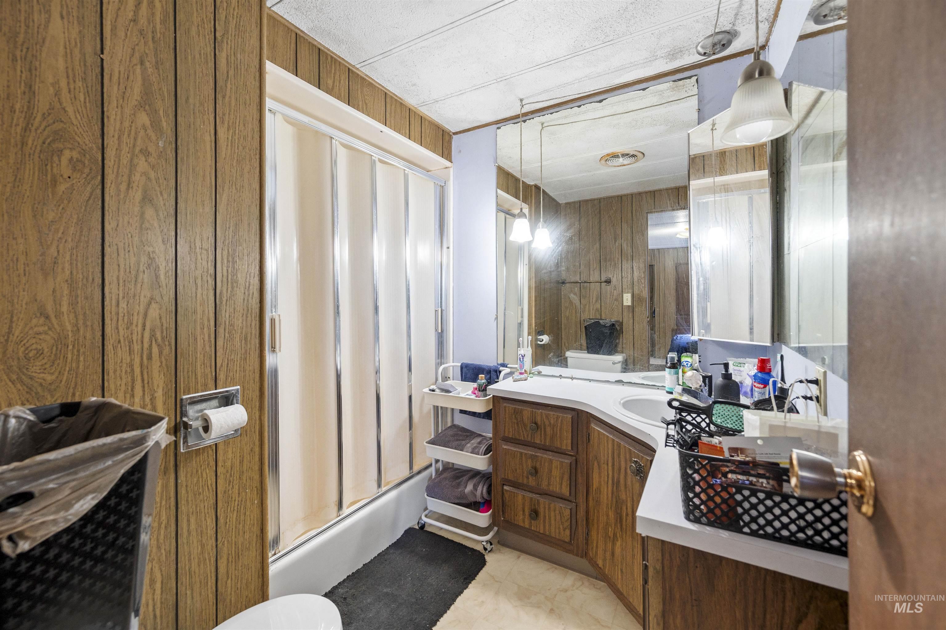 2382 East Syringa Street Eagle, ID 83616 - Photo 23 of 25 Bathroom featuring wood walls, vanity, and enclosed tub / shower combo