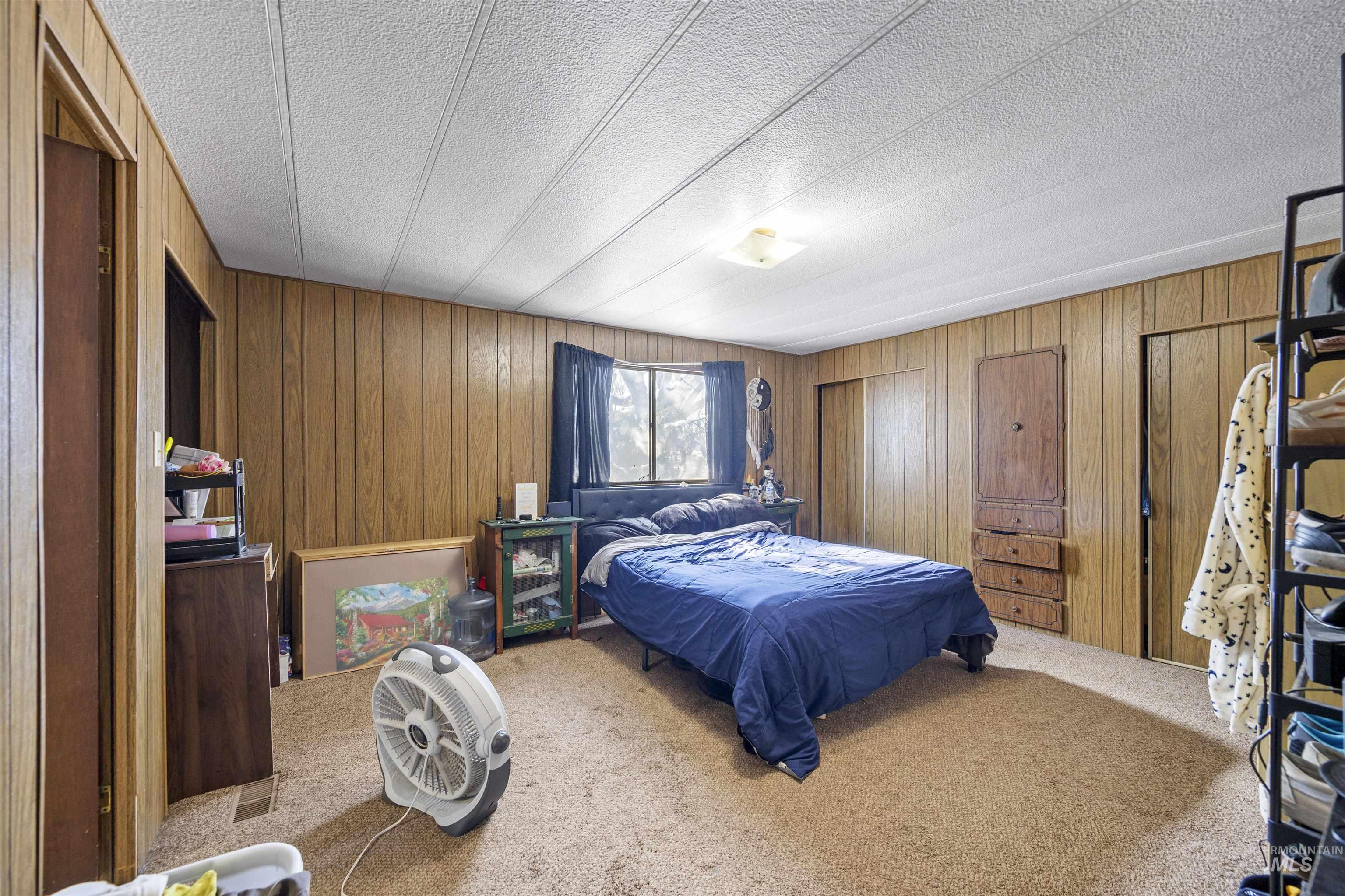 2382 East Syringa Street Eagle, ID 83616 - Photo 24 of 25 Carpeted bedroom featuring wood walls and a textured ceiling