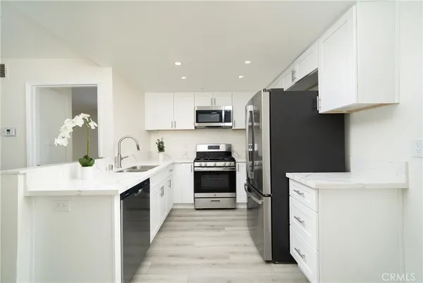 a kitchen with stainless steel appliances granite countertop a stove top oven a sink and a refrigerator