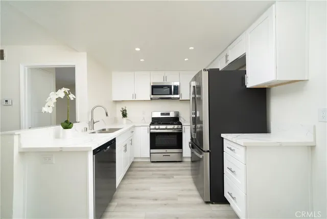 a kitchen with stainless steel appliances granite countertop a stove top oven a sink and a refrigerator