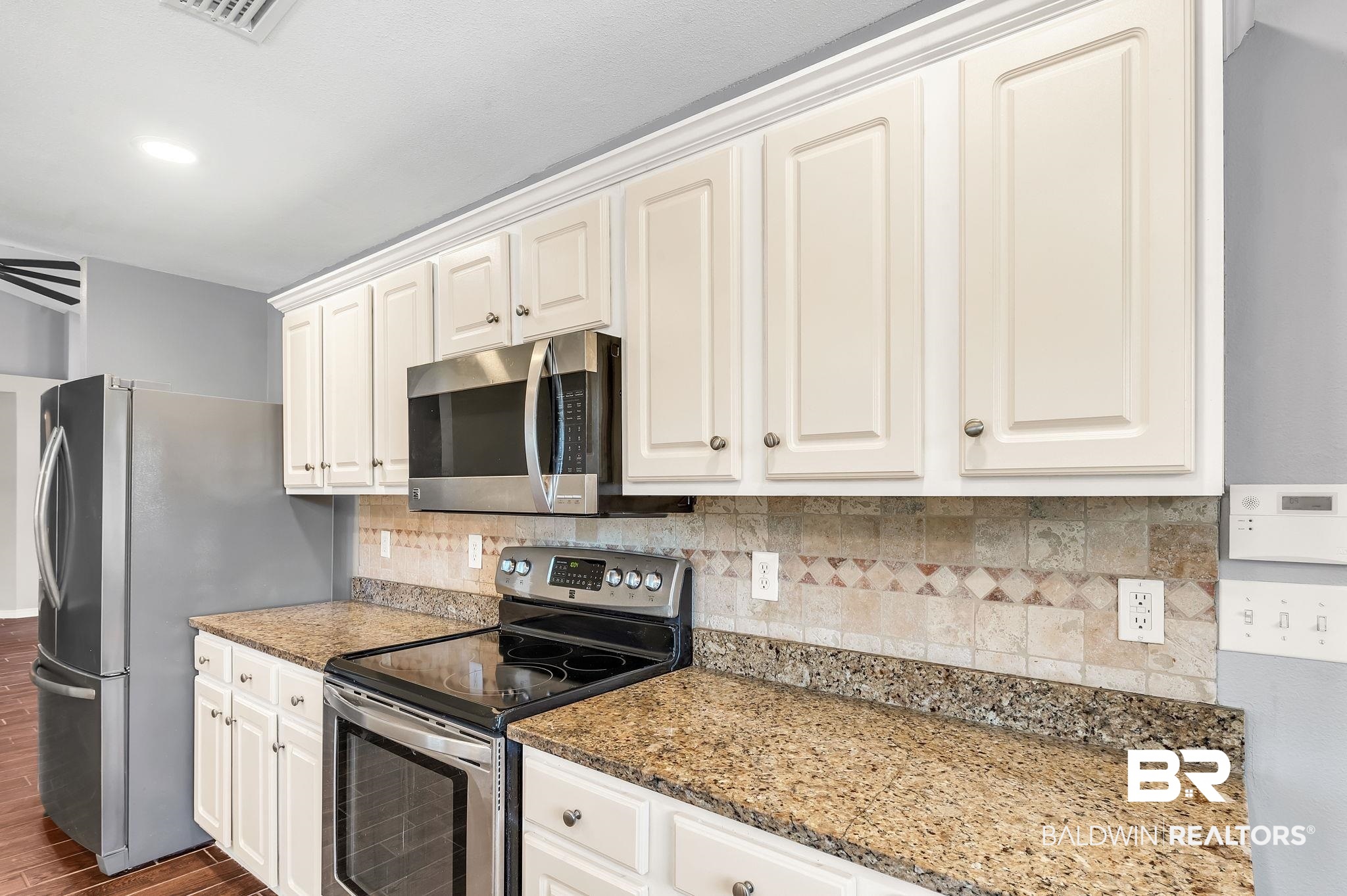 16444 Hamlet Lane Foley, AL 36535 - Photo 20 of 49 Kitchen with dark wood-style flooring, decorative backsplash, light stone counters, visible vents, and appliances with stainless steel finishes
