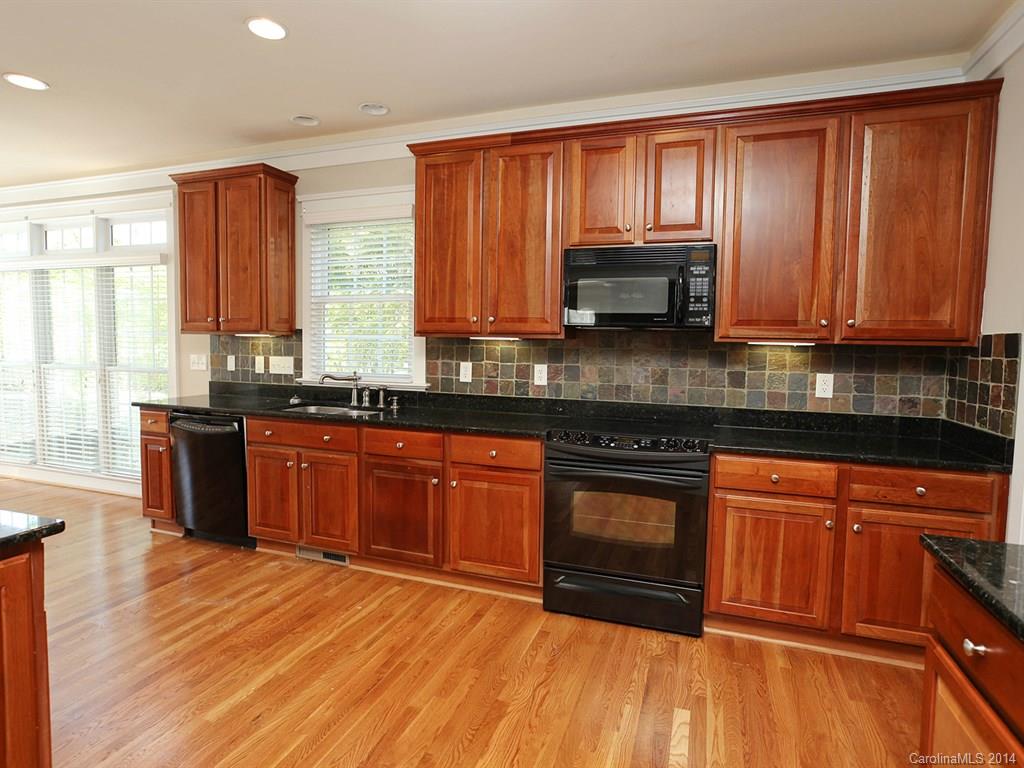 329 Third Baxter Street Fort Mill, SC 29708 - Photo 13 of 23 a kitchen with stainless steel appliances granite countertop wooden cabinets a stove a sink and dishwasher with wooden floor