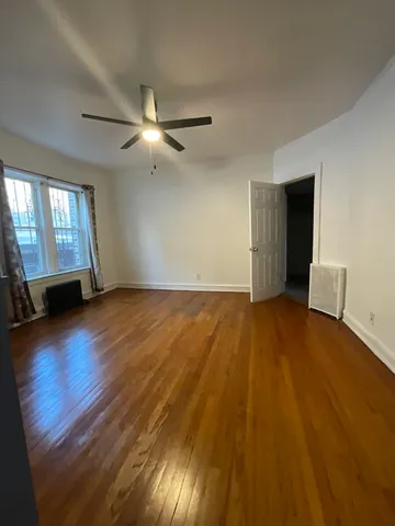 a view of empty room with wooden floor and fan