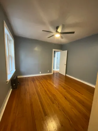a view of an empty room with window and wooden floor