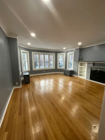 a view of empty room with wooden floor and fireplace