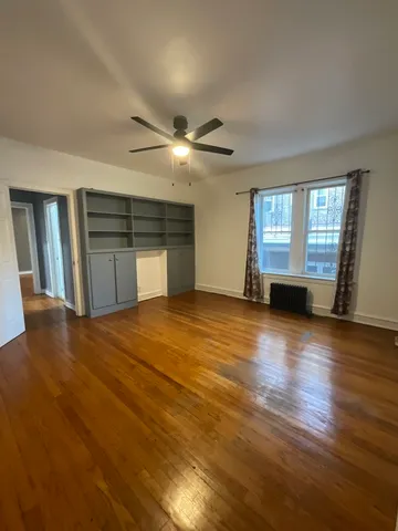 a view of an empty room with window and wooden floor