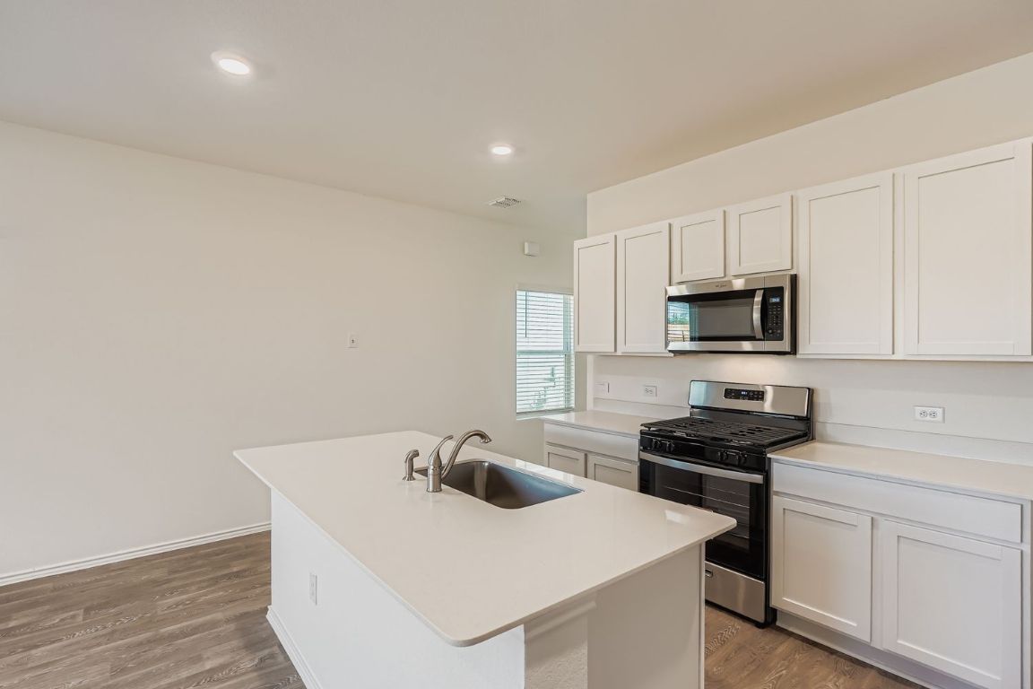 12112 Douglas Fir Circle Mustang Ridge, TX 78610 - Photo 11 of 33 a kitchen with stainless steel appliances a sink a stove and white cabinets
