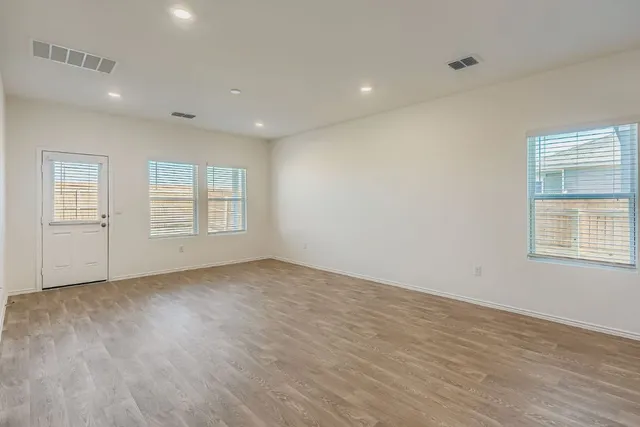 a view of an empty room with a window and wooden floor