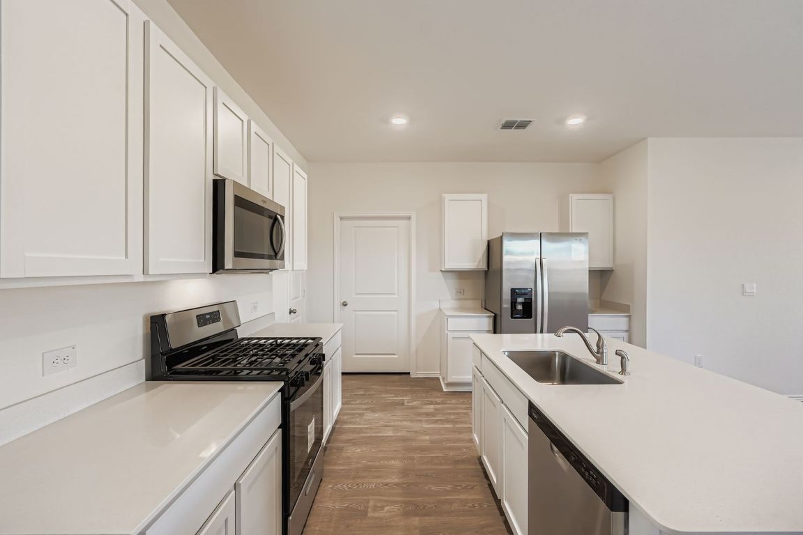 12112 Douglas Fir Circle Mustang Ridge, TX 78610 - Photo 15 of 33 a kitchen with stainless steel appliances a refrigerator stove microwave and sink
