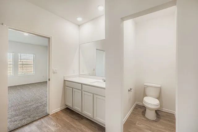 a bathroom with a granite countertop toilet a sink and a mirror