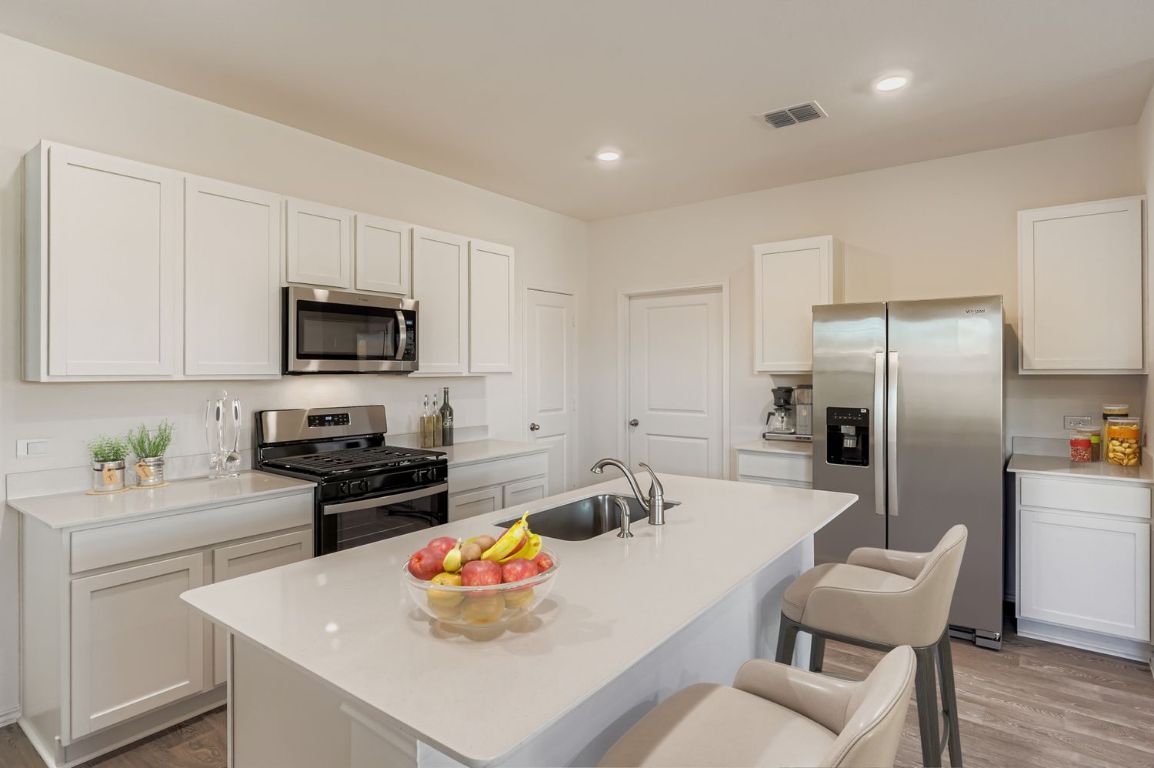 12112 Douglas Fir Circle Mustang Ridge, TX 78610 - Photo 5 of 33 a kitchen with a sink a stove and chairs