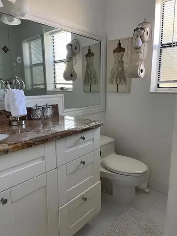 a bathroom with a granite countertop toilet sink and mirror