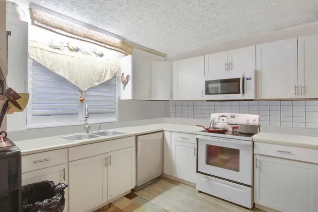 a kitchen with cabinets appliances a sink and a window