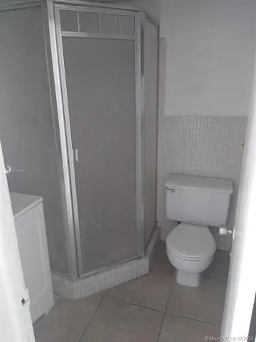 a white toilet sitting next to a shower