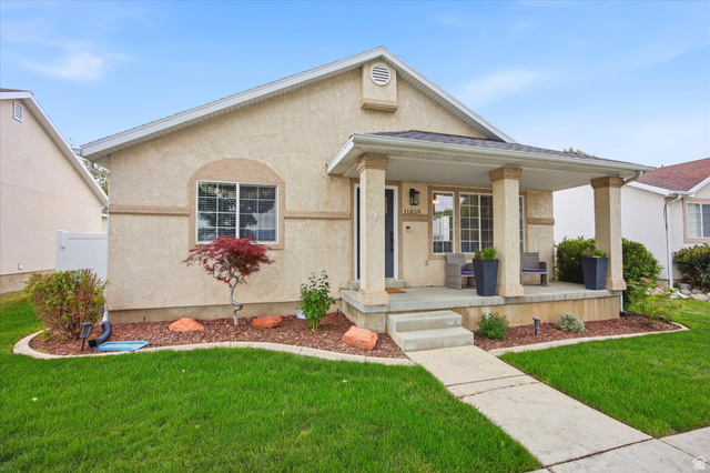 11859 Preamble Road Draper, UT 84020 - Photo 2 of 30 Stucco exterior featuring a covered porch with substantial pillars, a concrete walkway, and a landscaped front yard with a mature tree