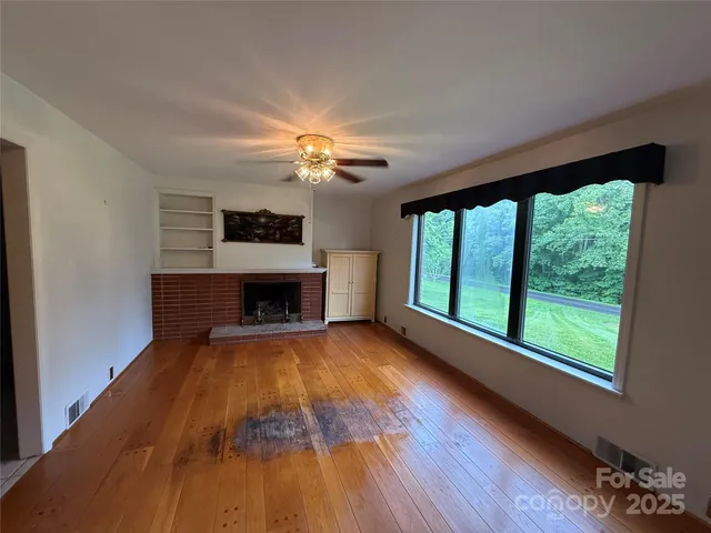a view of an empty room with a fireplace and a window