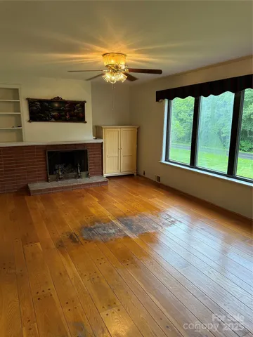 a view of an empty room with a window and wooden floor