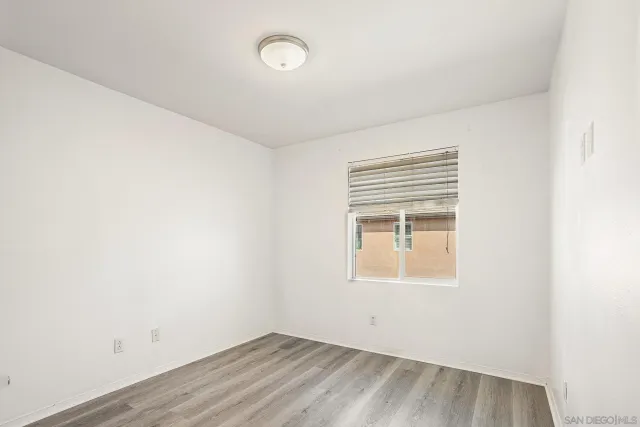 a view of an empty room with wooden floor and closet area