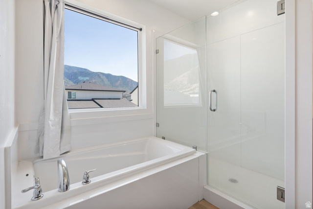 815 West Powderwood Lane Mapleton, UT 84664 - Photo 25 of 34 Soaking tub with chrome fixtures beneath a large window, complemented by a glass-enclosed shower with a contemporary handle