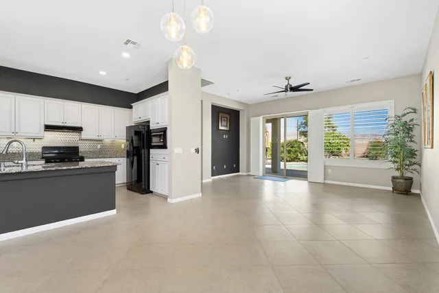 a living room with stainless steel appliances kitchen island granite countertop a refrigerator a stove a sink and a dining table with wooden floor