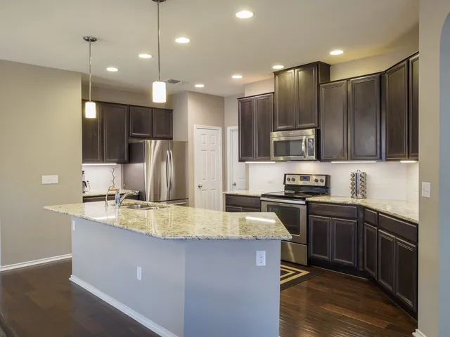 a kitchen with kitchen island granite countertop stainless steel appliances lots of counter space sink refrigerator and microwave