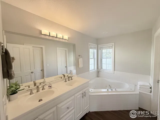 a bathroom with a sink double vanity granite tub shower and a mirror