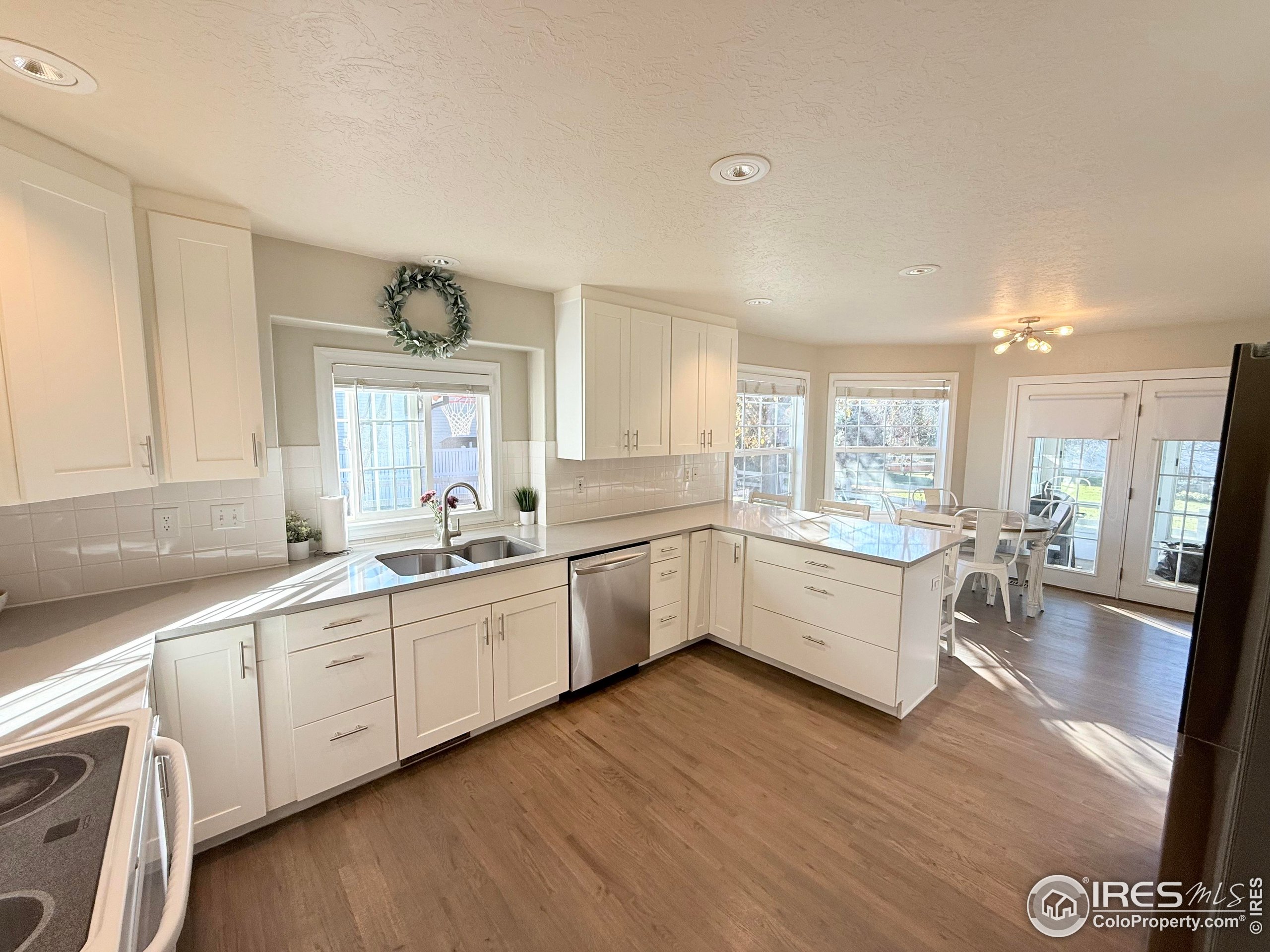 1460 Hawkridge Road Eaton, CO 80615 - Photo 5 of 20 a large white kitchen with cabinets a sink a window and stainless steel appliances