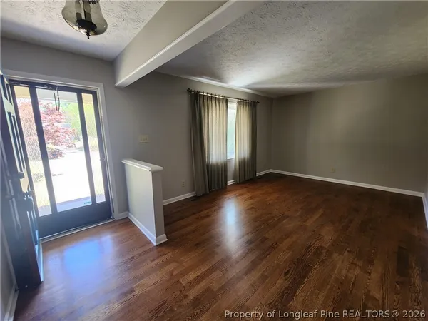 a view of an empty room with window and wooden floor