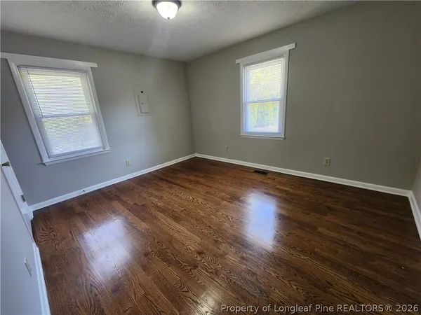 a view of empty room with wooden floor and fan