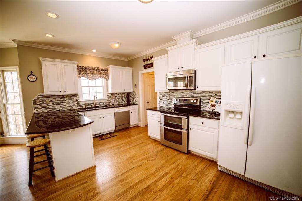 522 Zackery Lane Fort Mill, SC 29708 - Photo 5 of 24 a kitchen with granite countertop a refrigerator stove and wooden floor