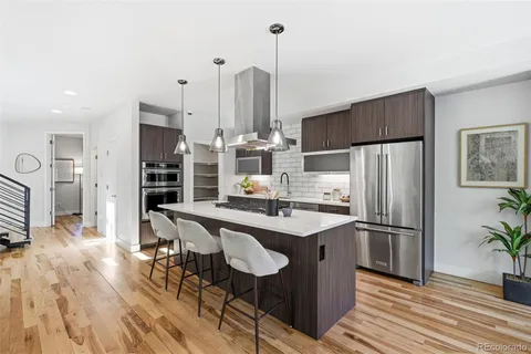a kitchen with stainless steel appliances a dining table chairs refrigerator and cabinets
