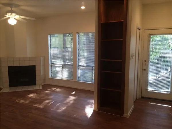 a view of an empty room with a window and wooden floor