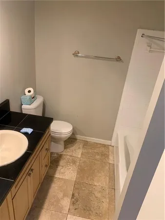 a bathroom with a granite countertop sink a toilet a mirror and shower