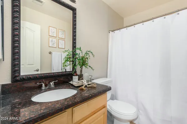 a bathroom with a granite countertop sink and a mirror with toilet