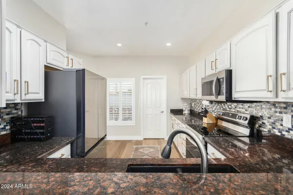 a kitchen with granite countertop a stove a sink and a refrigerator