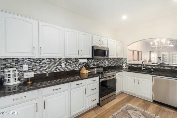 a kitchen with granite countertop white cabinets and white appliances