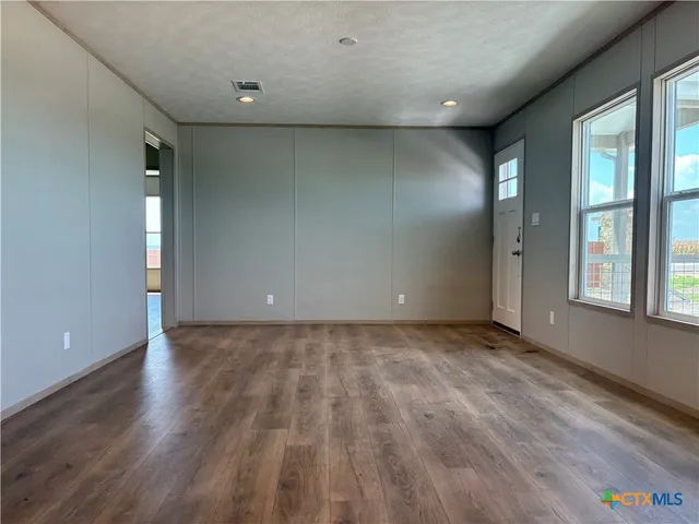 a view of an empty room with glass door and wooden floor