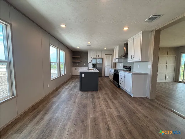 a large kitchen with wooden floors and stainless steel appliances
