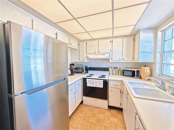 a kitchen with stainless steel appliances granite countertop a refrigerator a sink dishwasher a stove with white cabinets and wooden floor